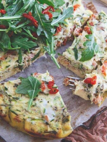 This slow cooker frittata is bursting with grated zucchini, sun dried tomatoes, basil and prosciutto then topped with a simple arugula salad. Great for a summer breakfast or dinner!