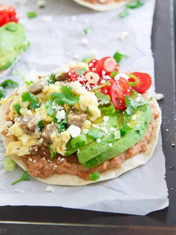 These breakfast tostadas include chicken sausage scrambled eggs piled high on a refried bean base. Avocado, tomatoes and cotija top it all off!