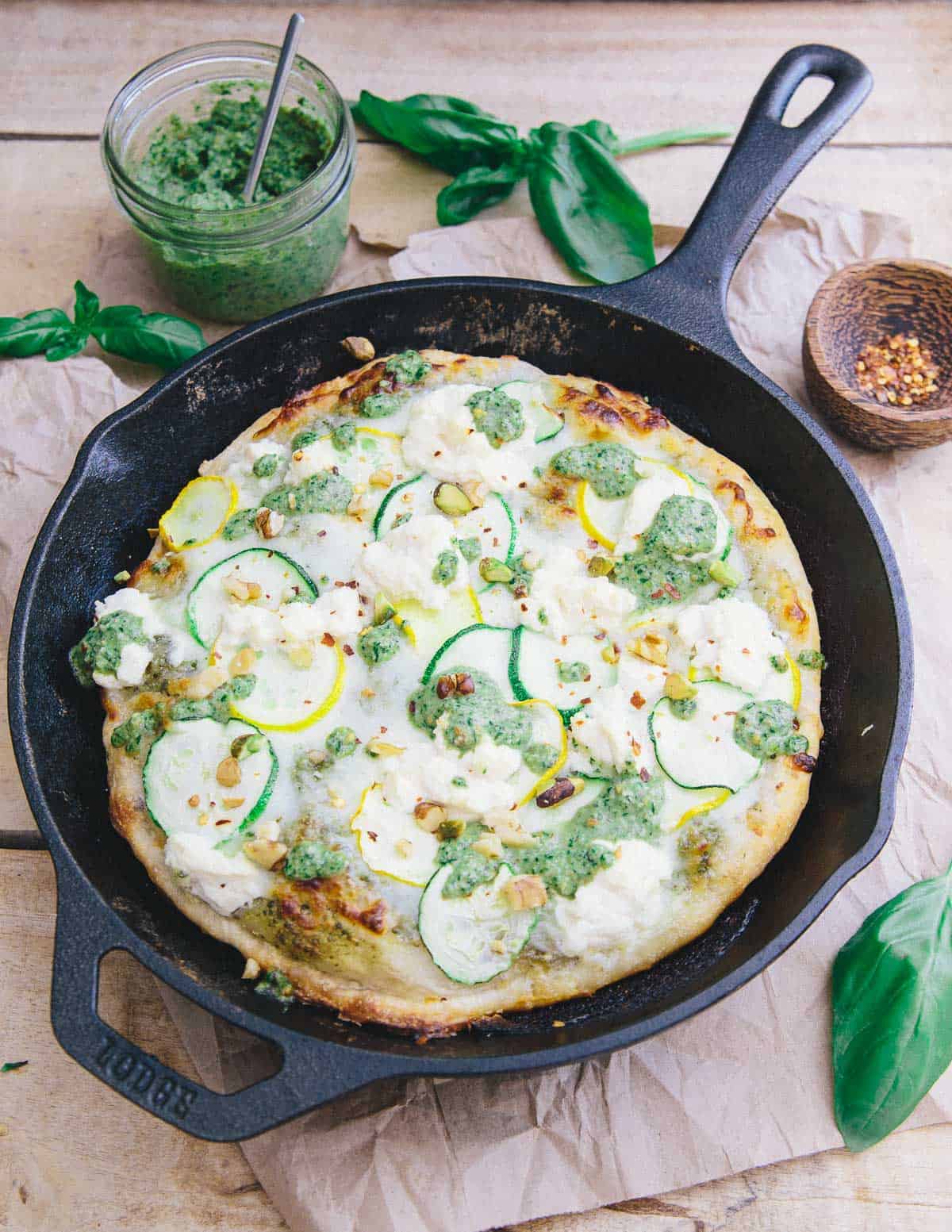 This skillet zucchini pesto pizza has a crispy yet chewy crust. With layers of tangy basil pesto, mozzarella, zucchini and ricotta it's perfect for summer!