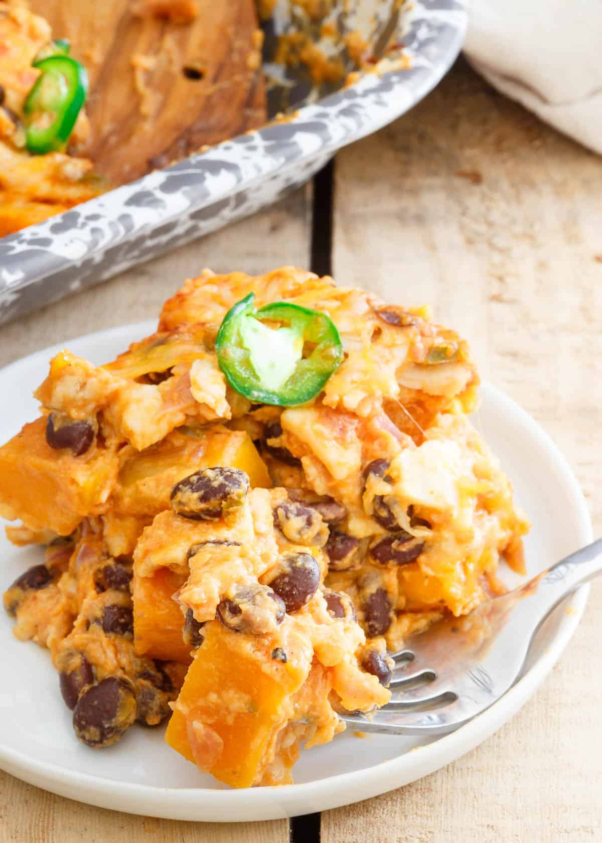 A serving of pumpkin casserole on a small white plate with a fork.