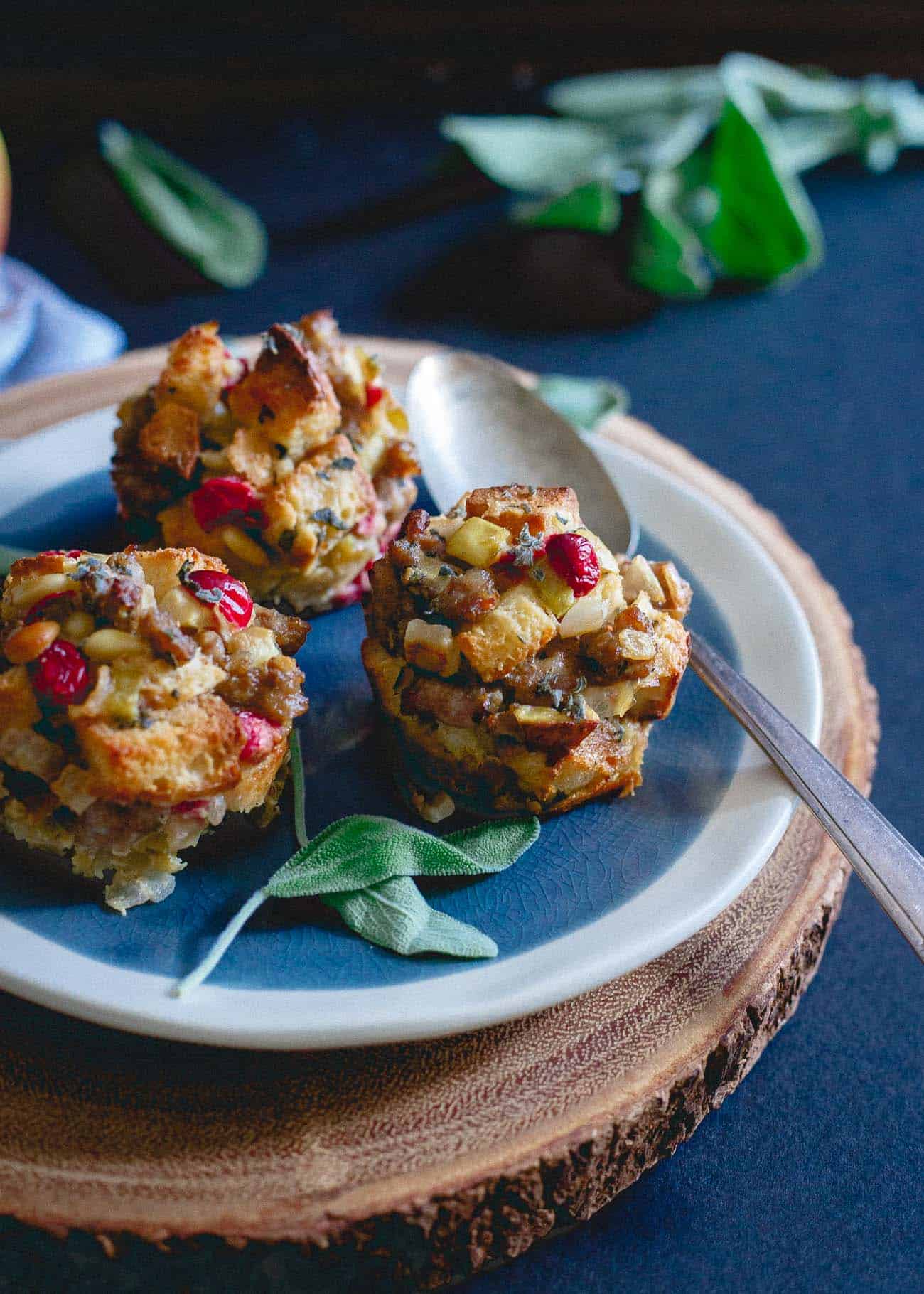 Side view of easy sausage stuffing muffins on a plate next to a spoon.