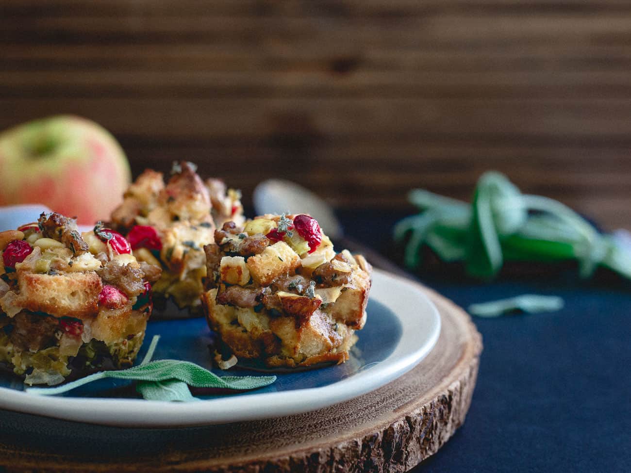 Sausage cranberry apple stuffing muffins on a plate next to an apple.