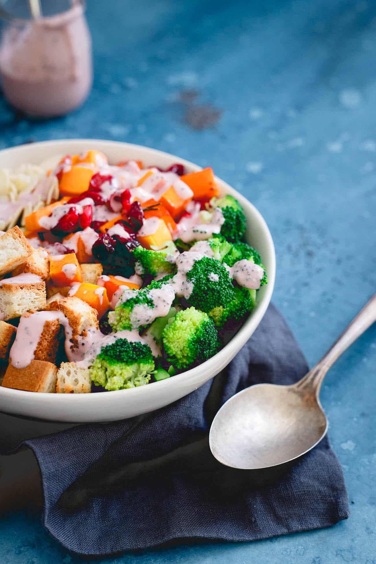 Cranberry broccoli salad in a white bowl next to a spoon.