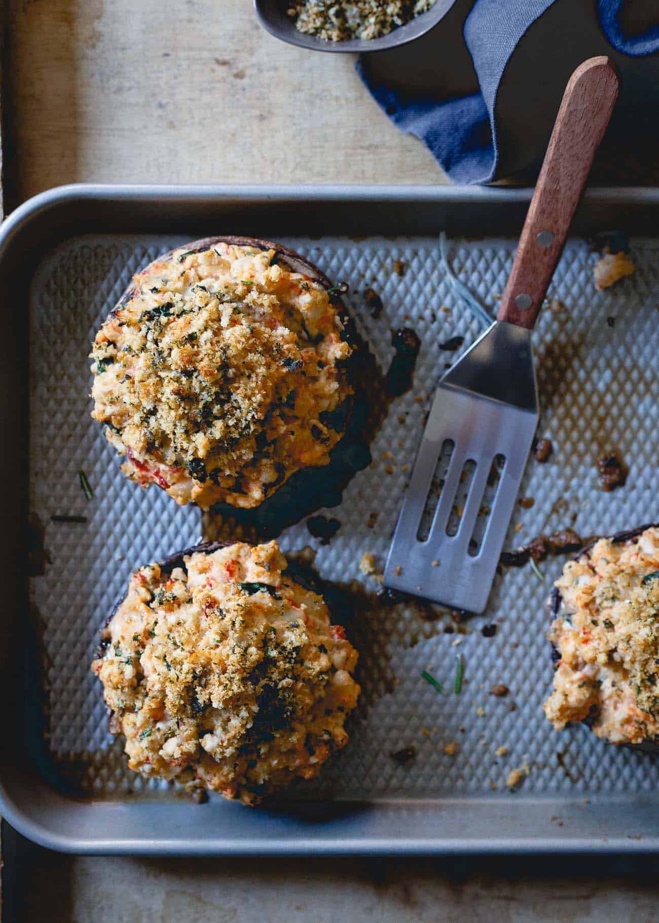 Ground turkey stuffed mushrooms on a pan next to a small spatula.