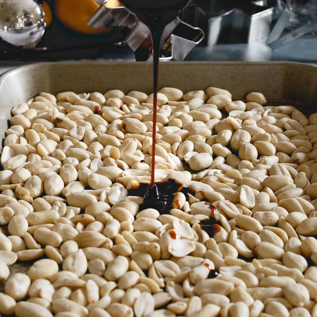 Pouring molasses over raw peanuts before roasting.