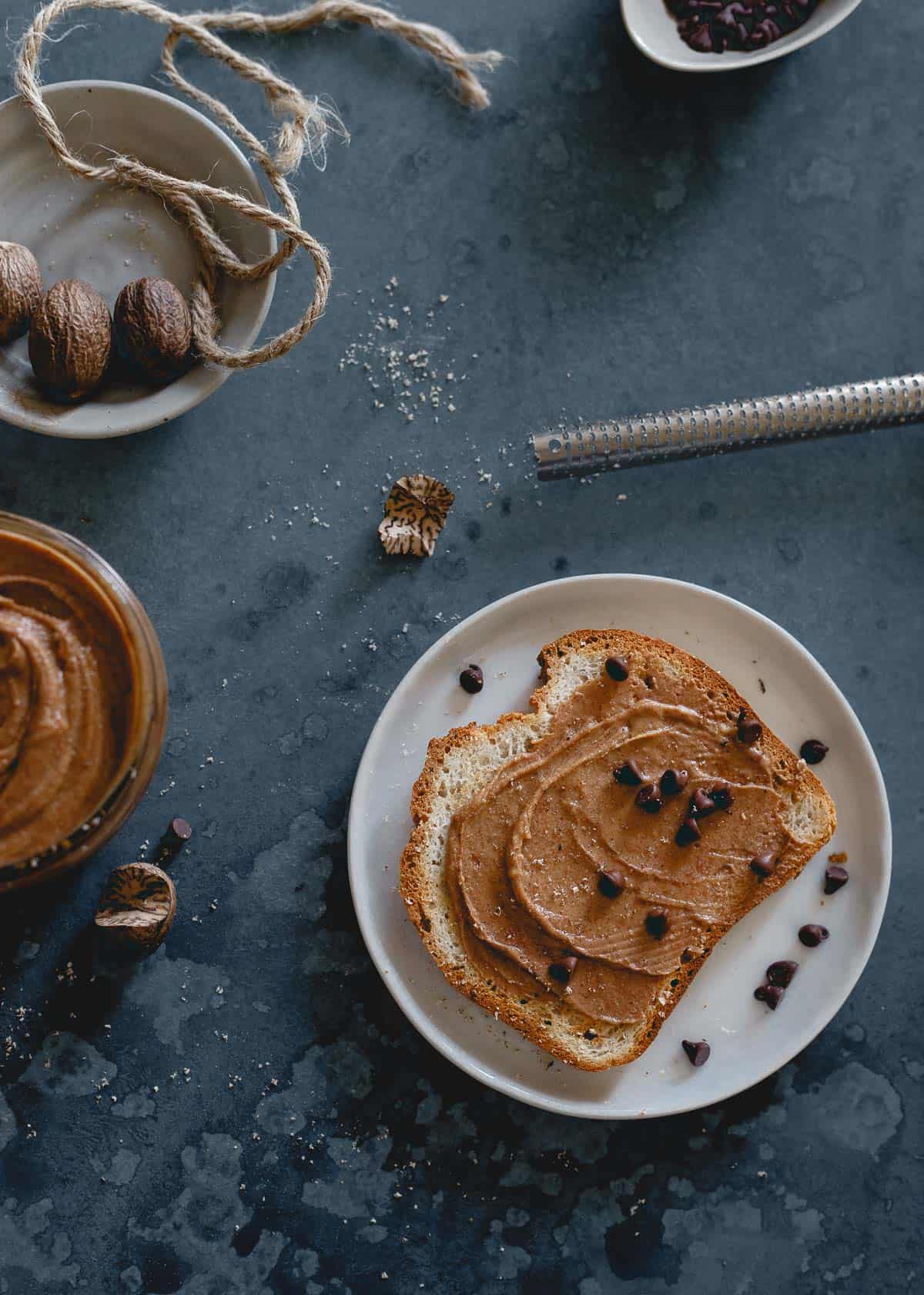 Gingerbread nut butter on toast on a white plate with mini chocolate chips.