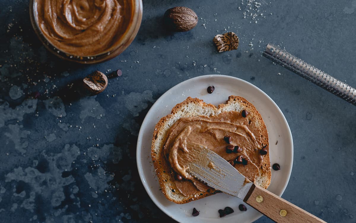 Spreading gingerbread butter on toast using a spatula.