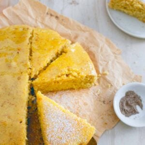 Orange cardamom cake sliced on parchment paper.