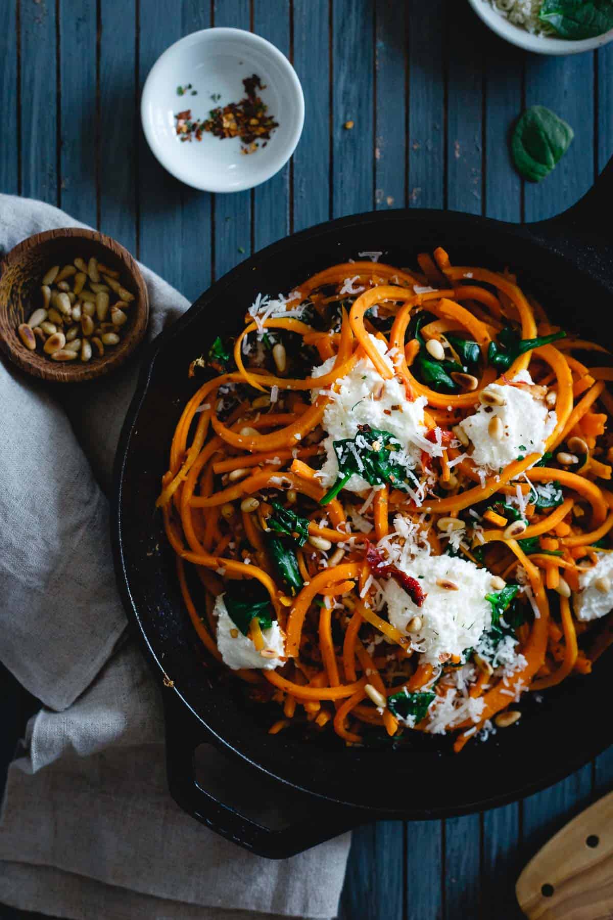 These garlicky butternut squash noodles are tossed with wilted spinach, sun-dried tomatoes, toasted pine nuts and dollops of fresh ricotta and parmesan for a wintry, one-pan, comforting vegetarian meal. 