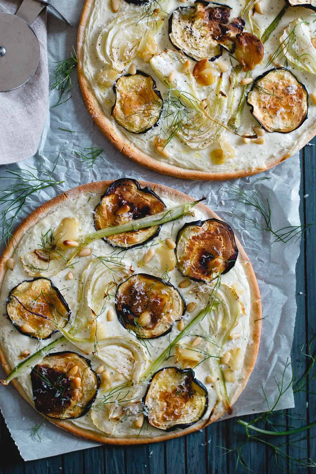 If you love white pizza, you'll love this roasted eggplant fennel pizza! It has a whipped feta and ricotta base with toasted pine nuts, creamy roasted garlic cloves and an olive oil drizzle to top it off.