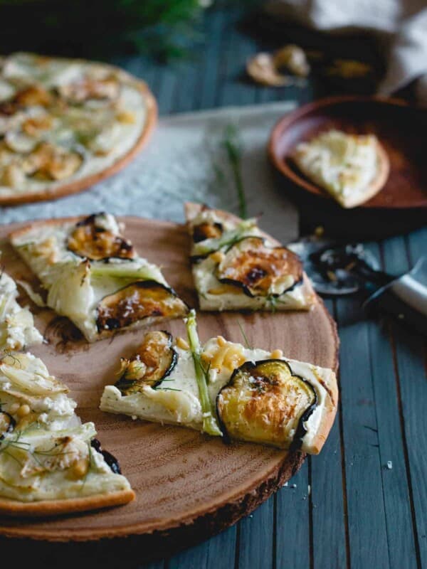 If you love white pizza, you'll love this roasted eggplant fennel pizza! It has a whipped feta and ricotta base with toasted pine nuts, creamy roasted garlic cloves and an olive oil drizzle to top it off.