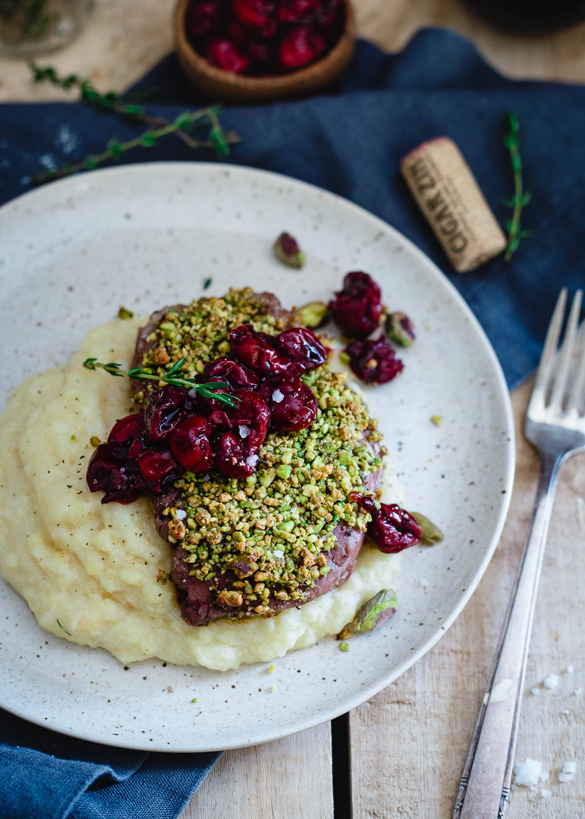 Pistachio crusted lamb chops are topped with a simple red wine cherry sauce and served over creamy parmesan polenta. It's fancy food made simple and perfect for a special Valentine's Day dinner.