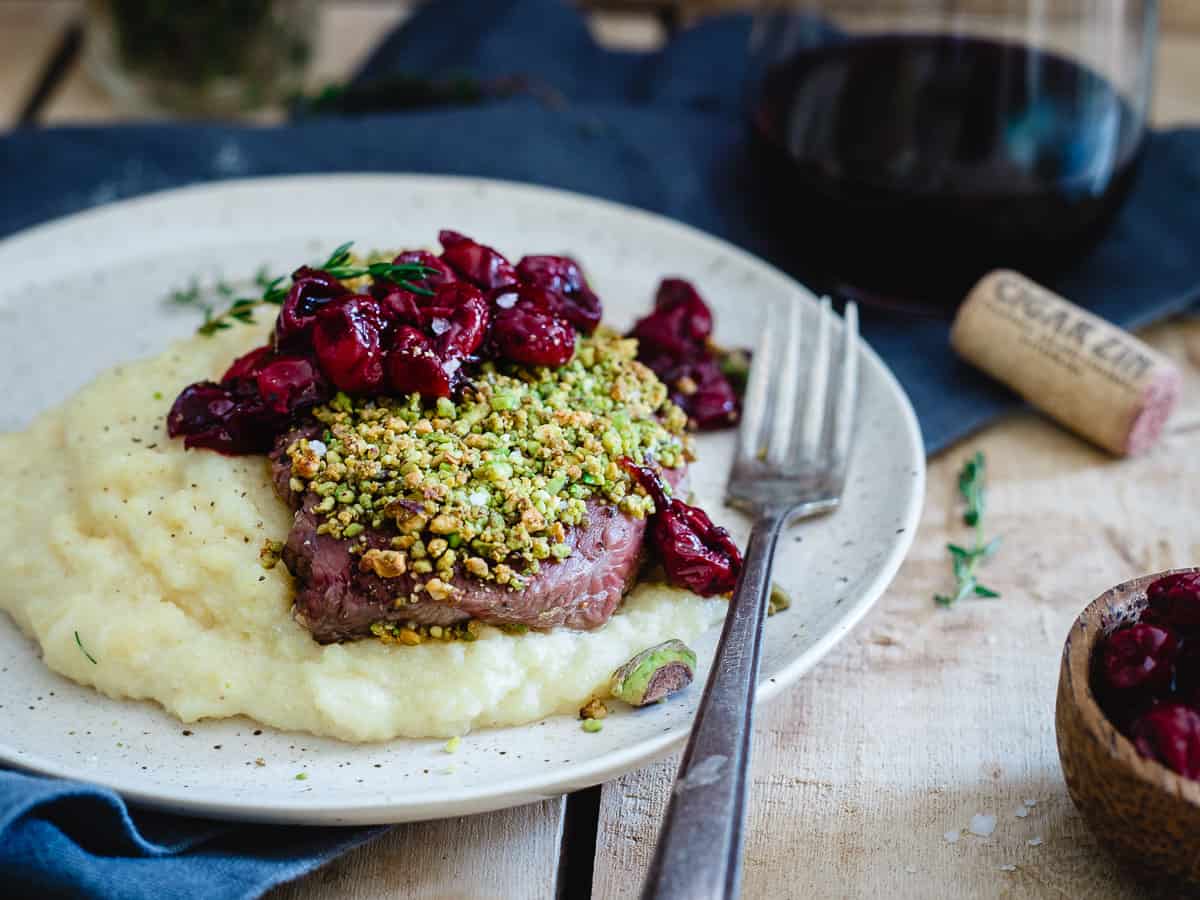 Looking for a fancy Valentine's Day dinner that's actually simple? These pistachio crusted lamb chops with red wine cherries will impress!