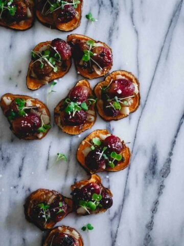 These roasted sweet potato crostini are topped with vegan friendly jalapeno havarti style cheese, roasted grapes and caramelized onions. Finished with sea salt and micro greens, they're an appetizer everyone can enjoy!