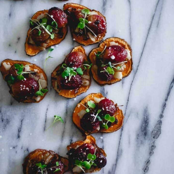 These roasted sweet potato crostini are topped with vegan friendly jalapeno havarti style cheese, roasted grapes and caramelized onions. Finished with sea salt and micro greens, they're an appetizer everyone can enjoy!