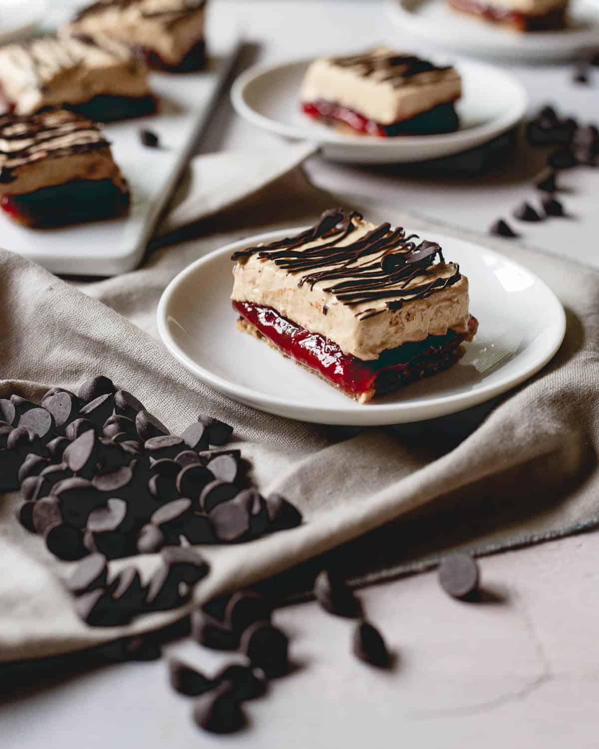 These peanut butter and jelly frozen yogurt bars have a chewy granola bar base and layers of sweet strawberry jelly, creamy peanut butter yogurt and a chocolate drizzle topping.