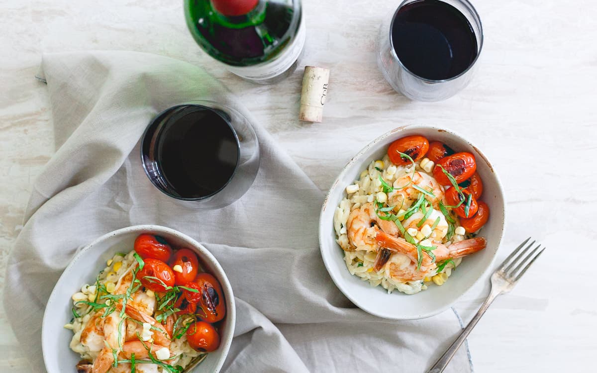 A bed of creamy parmesan orzo with summer corn and basil is topped with simple brown butter shrimp for an easy, elegant summer meal.