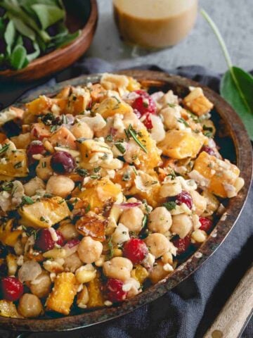 This chickpea fall salad is a hearty vegetarian meal with roasted sweet potatoes, delicata squash, cranberries, feta and a maple tahini dressing.