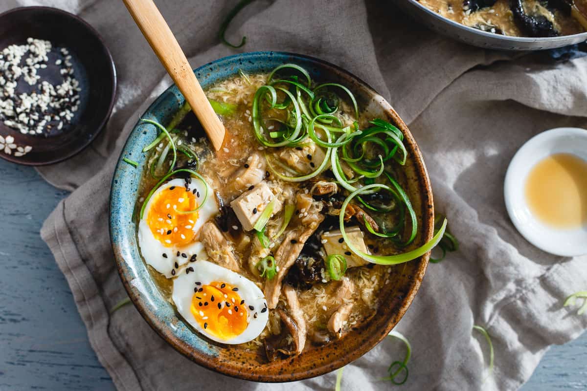 A bowl of soup with an egg on top.