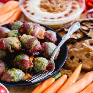 These bacon wrapped brussels sprouts are glazed with maple syrup for a salty, sweet bite. Serve them for game-day with a spread of hummus, vegetables and other dippers!