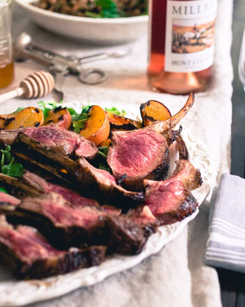 Grilled lamb chops with a sweet peach honey glaze are served with a simple watercress and peach salad for easy summer entertaining.