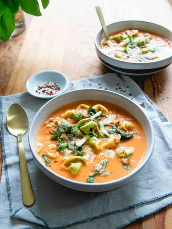 Two bowls of soup on a wooden table.