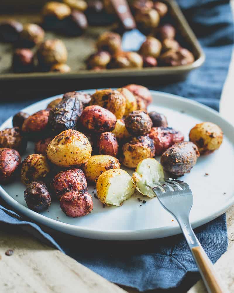 Roasted Portuguese baby potatoes with peri peri seasoning on a white plate with a fork.