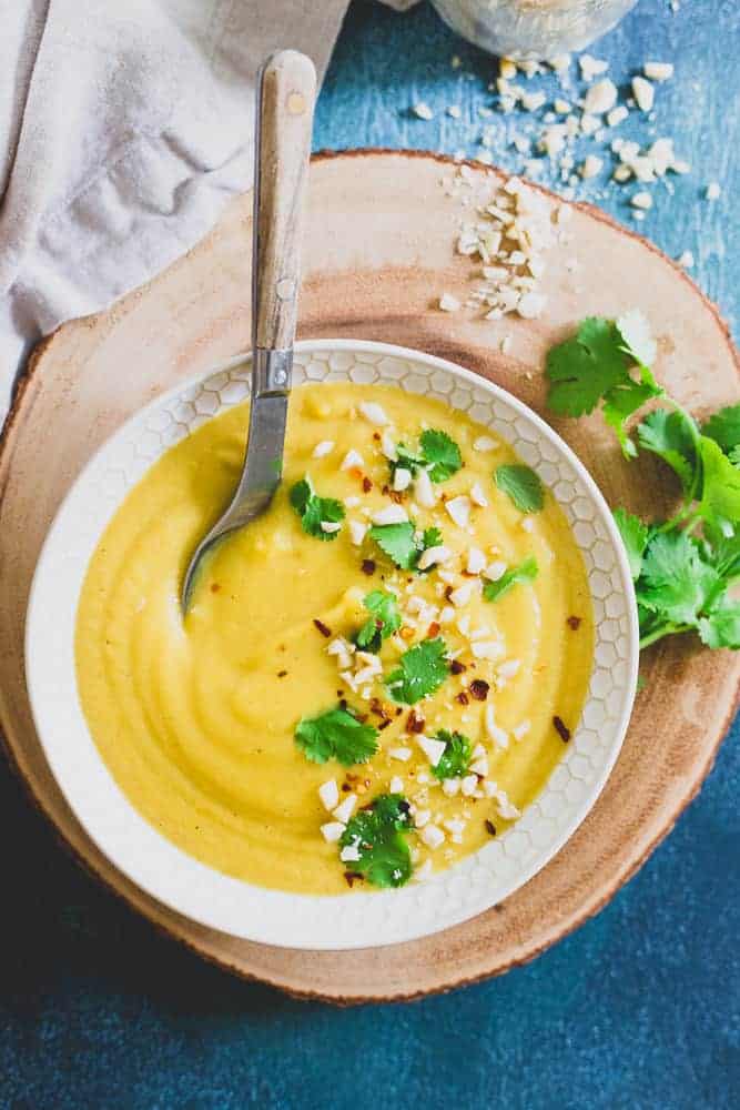 Creamy delicata squash soup in a bowl with a spoon.