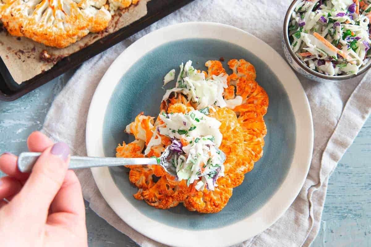 Top easy buffalo cauliflower steaks with a creamy blue cheese coleslaw for a delicious healthier buffalo sauce inspired meal.