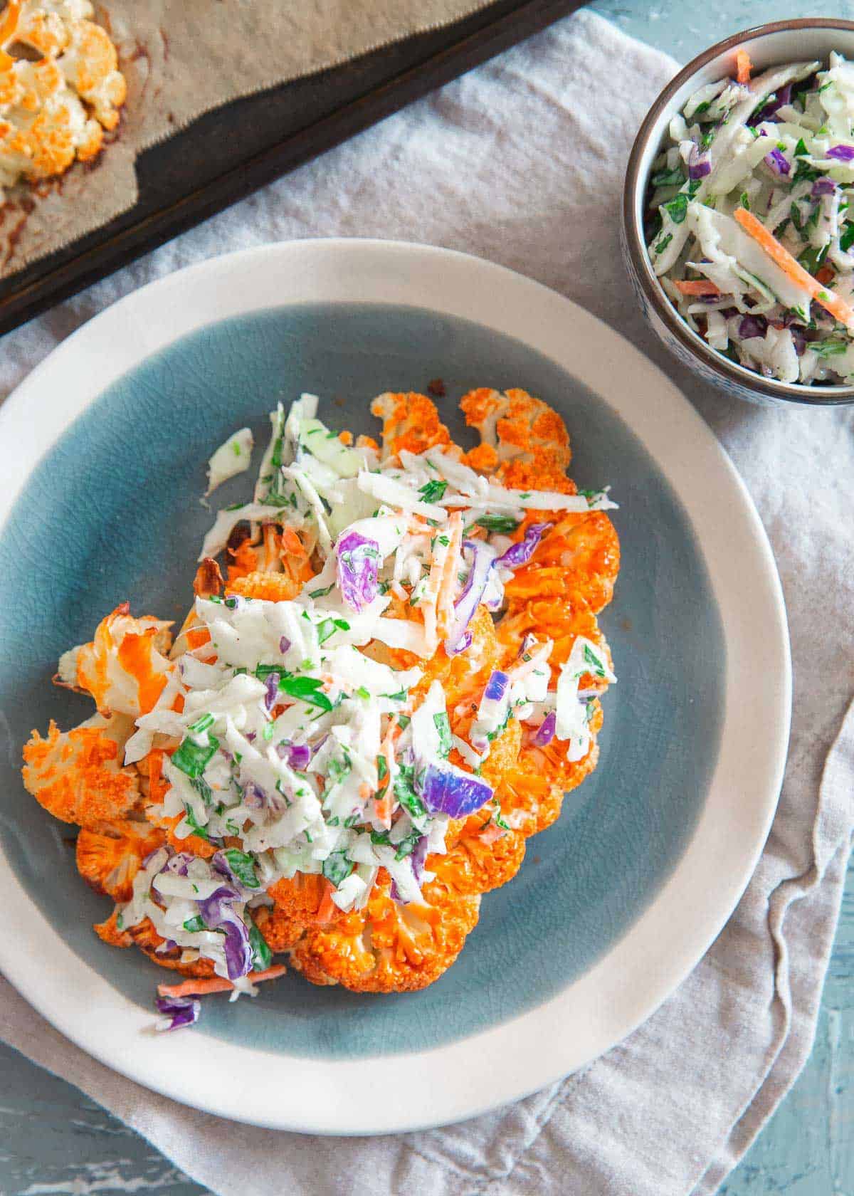 Buffalo sauce roasted cauliflower steaks are topped with a blue cheese coleslaw for a healthy game day bite!