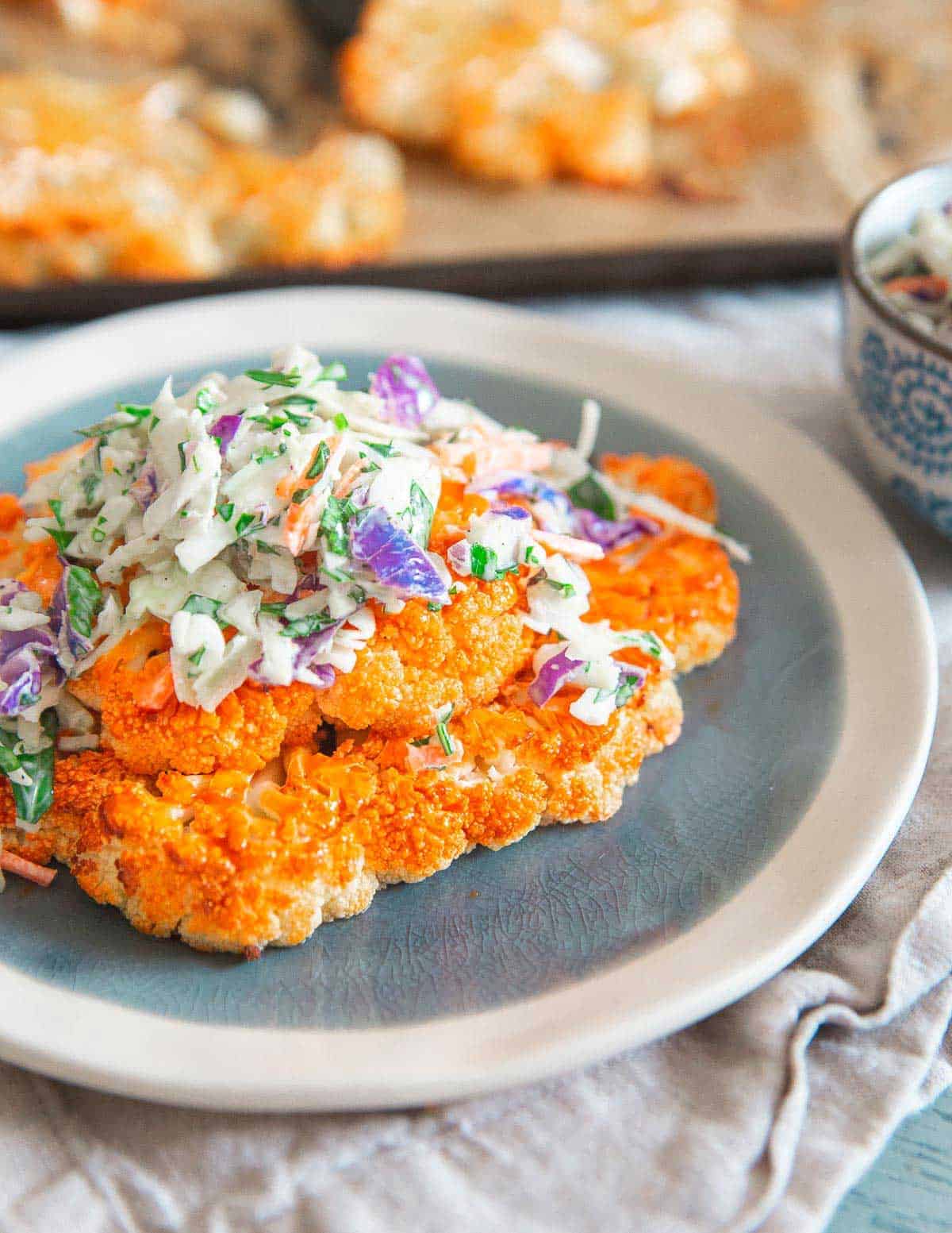 These roasted buffalo cauliflower steaks are topped with a creamy blue cheese coleslaw. Enjoy the flavor of buffalo sauce for game day with a healthy twist!