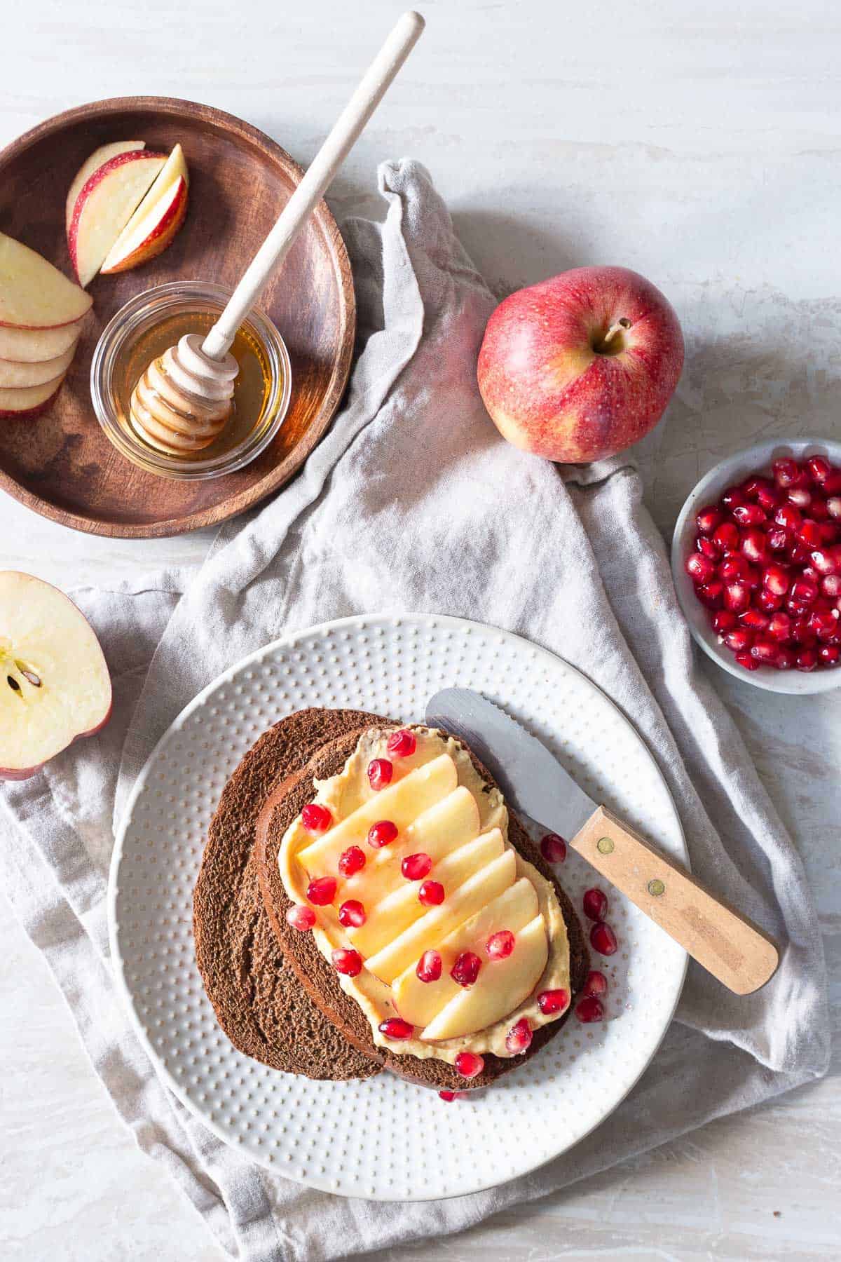 Honey apple hummus toast with pomegranates is a fun and quick winter snack idea.