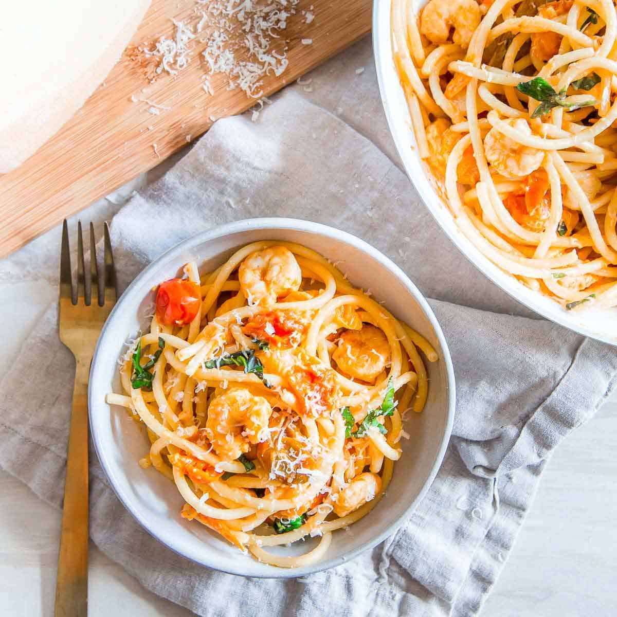 This easy bucatini pasta recipe tossed with garlic shrimp and cherry tomatoes is made in under 30 minutes making it a great weeknight meal.