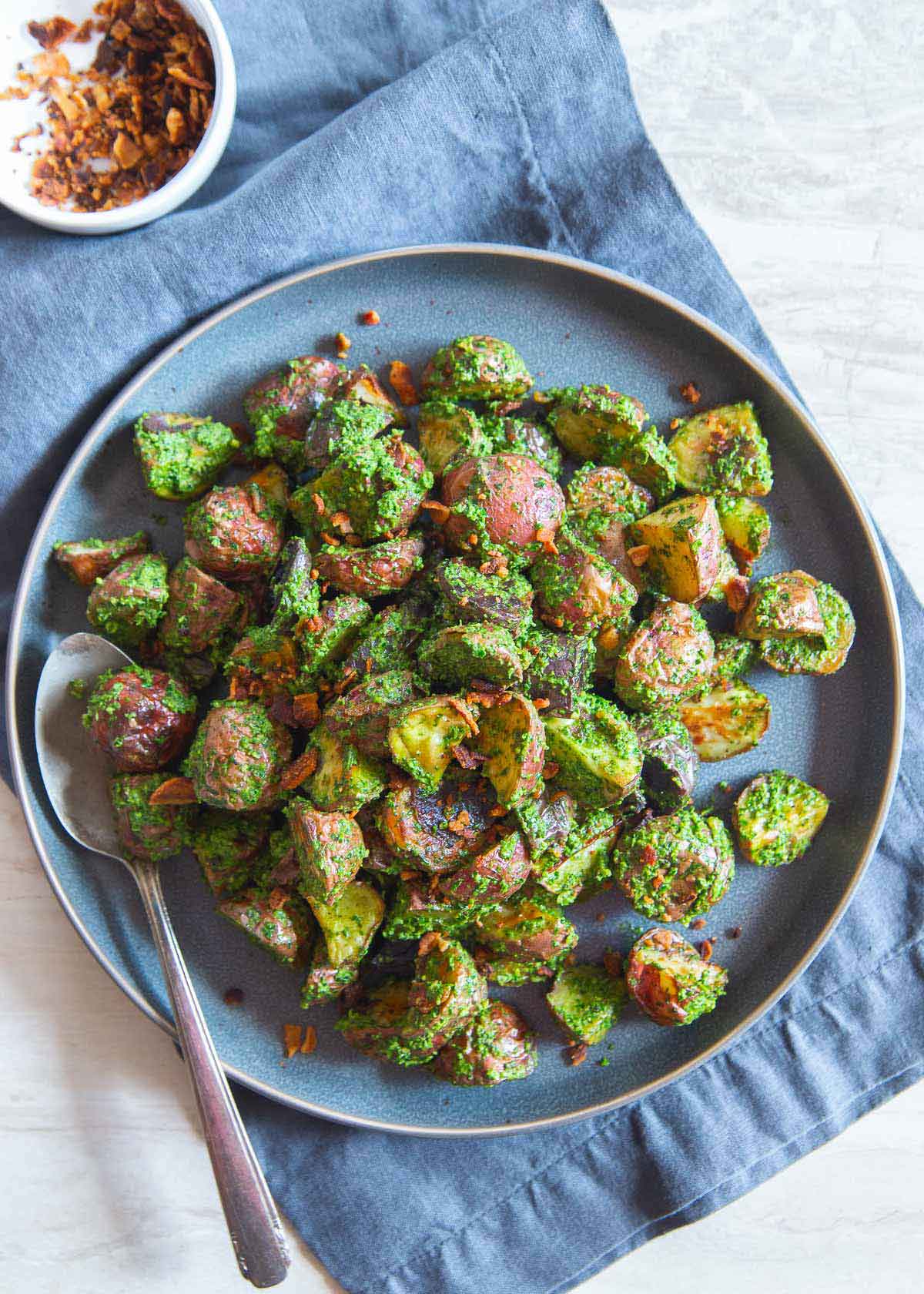 Pesto potatoes are an easy side dish that go with almost any meal. Crispy bacon bits bring a salty bite!