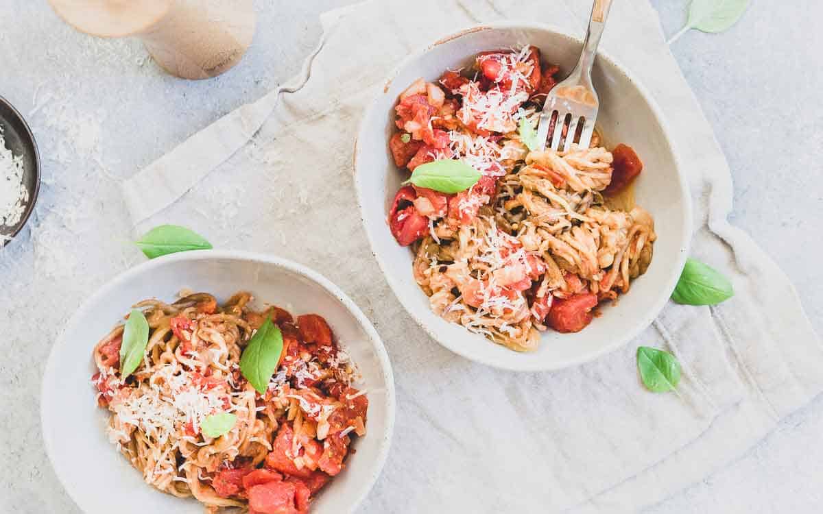 Spiralized eggplant noodles tossed with a quick summer fresh tomato basil sauce and parmesan cheese.
