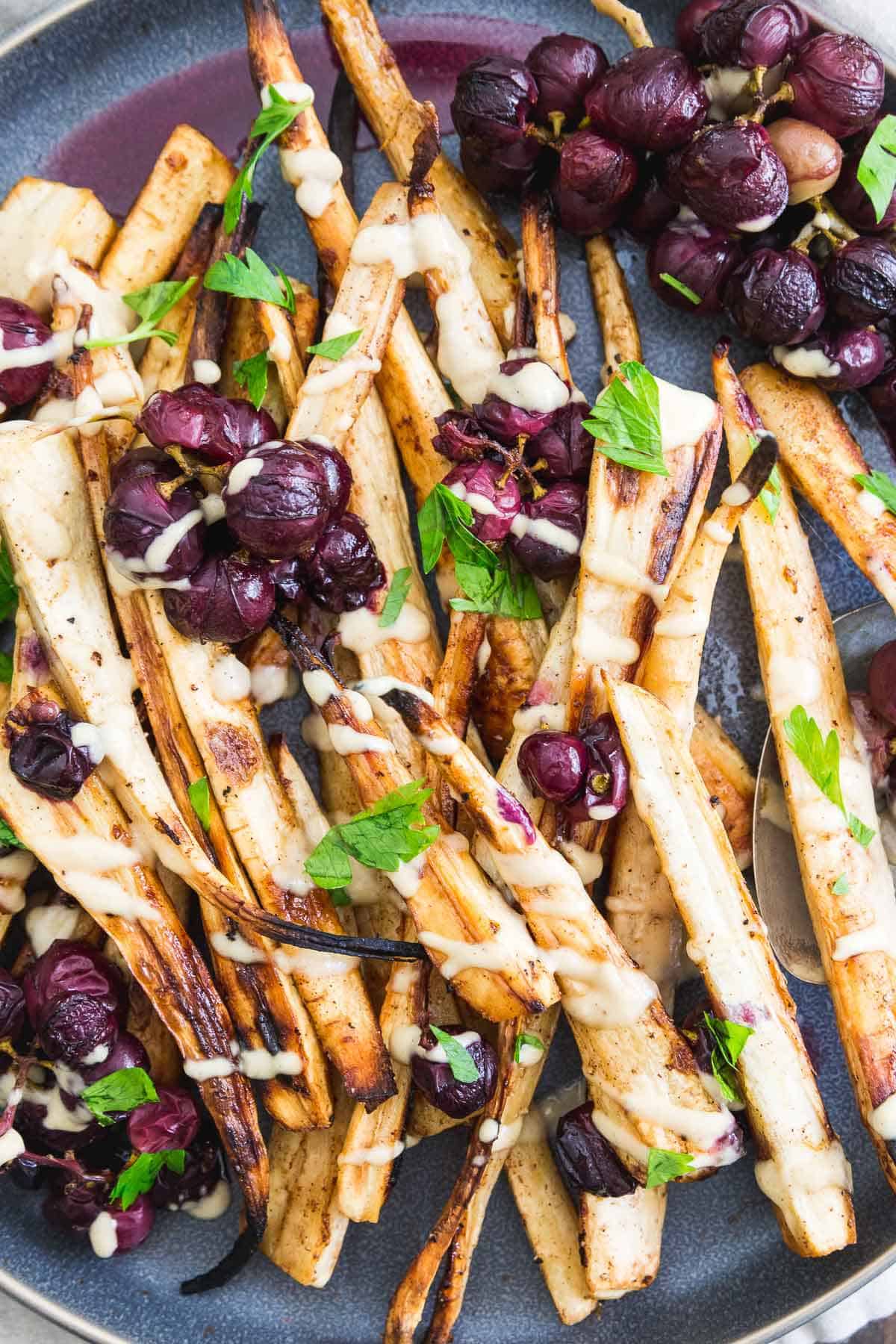 Cinnamon sugar roasted parsnips with concord grapes and a sweet maple hummus drizzle make a delicious and impressive holiday side dish. 