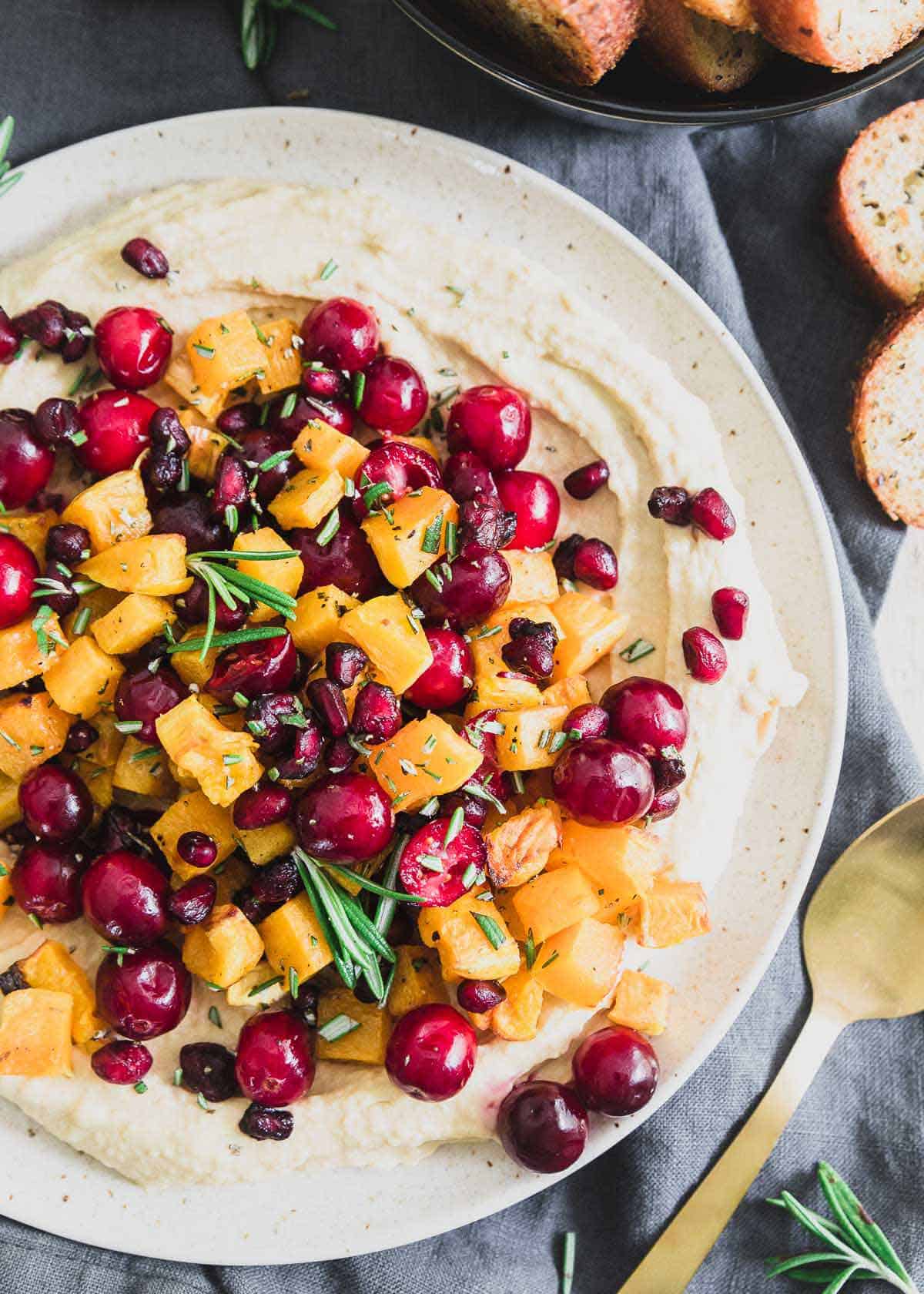 A holiday hummus recipe with butternut squash, cranberries, pomegranates and fresh rosemary.