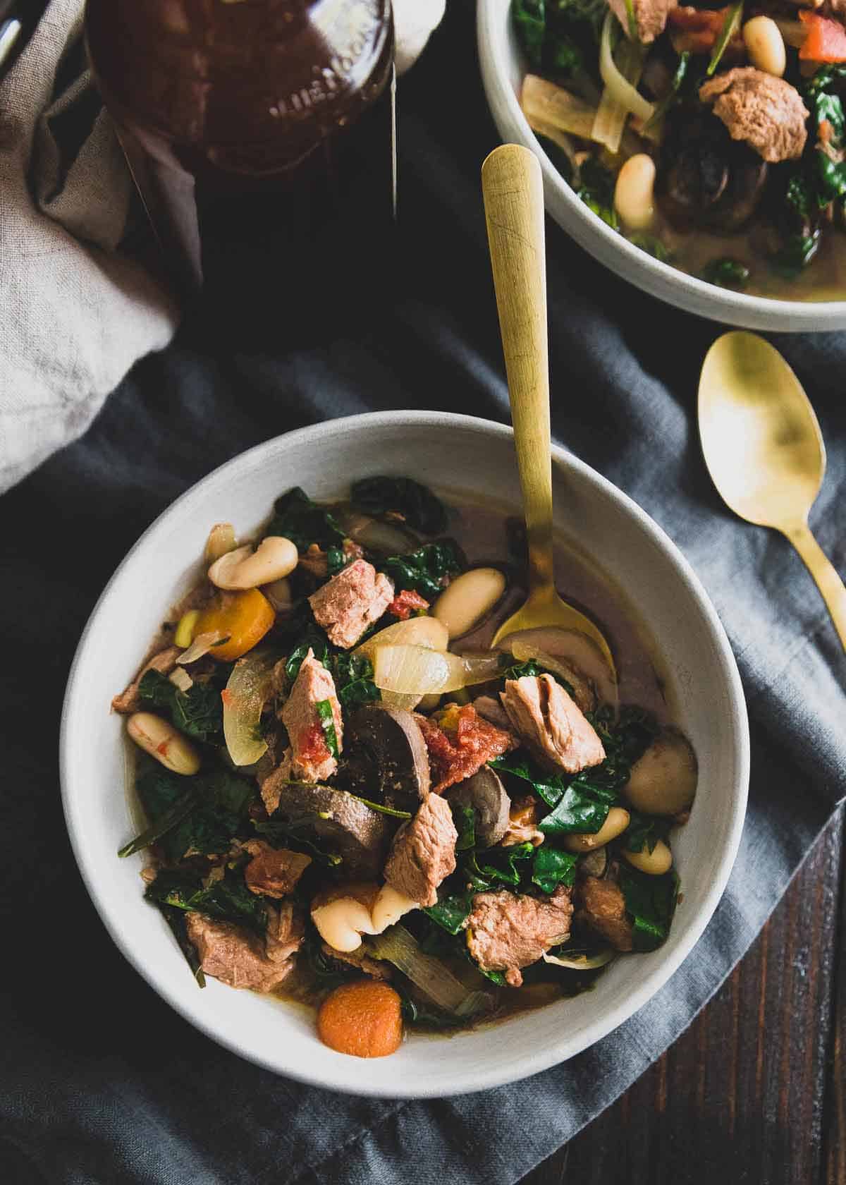 This slow cooker lamb stew is a hearty, cozy bowl of comfort made with lean American lamb stew meat, mushrooms, white beans, kale, tomatoes and rosemary.