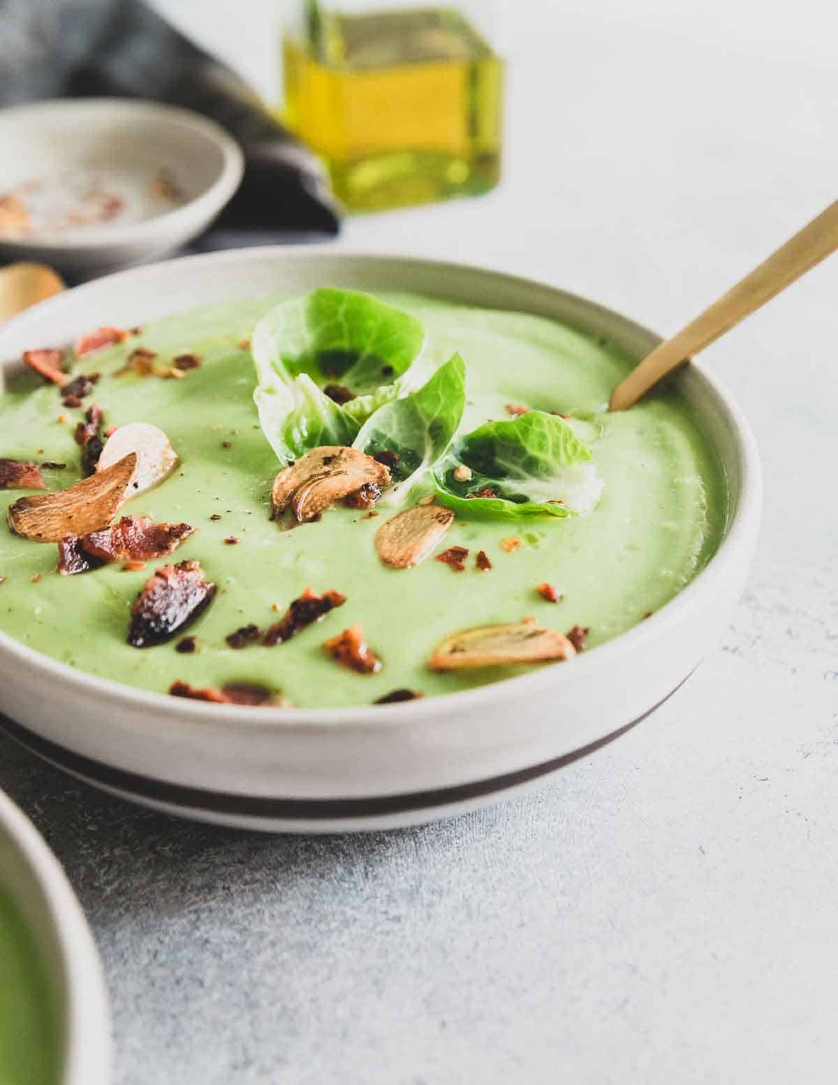 A creamy Brussels sprout soup packed with lots of garlic flavor and garnished with crispy bacon and fried garlic chips.