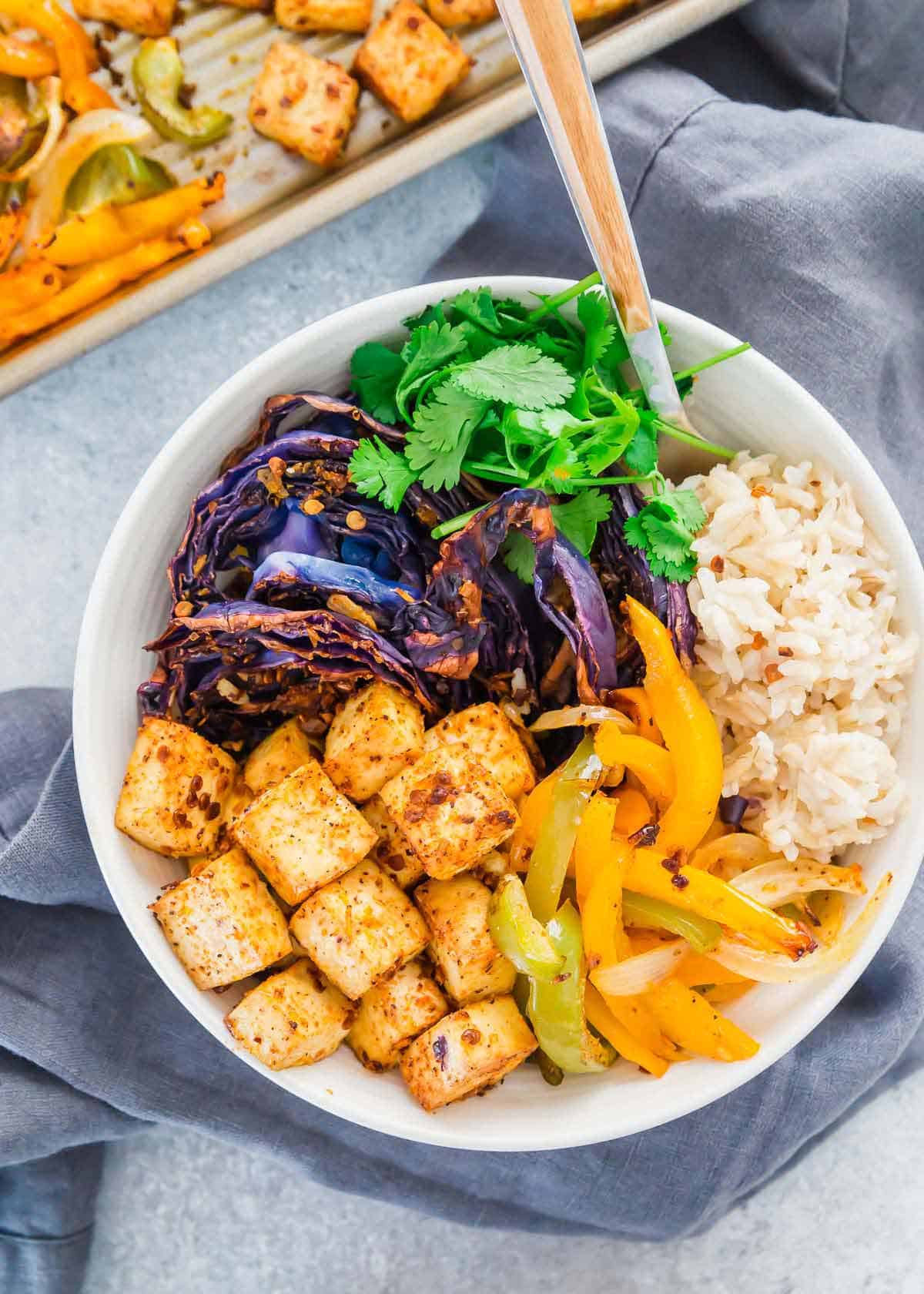 Crispy roasted tofu meal prep with cabbage, peppers, onions and brown rice made on a sheet pan is easy and nutritious.