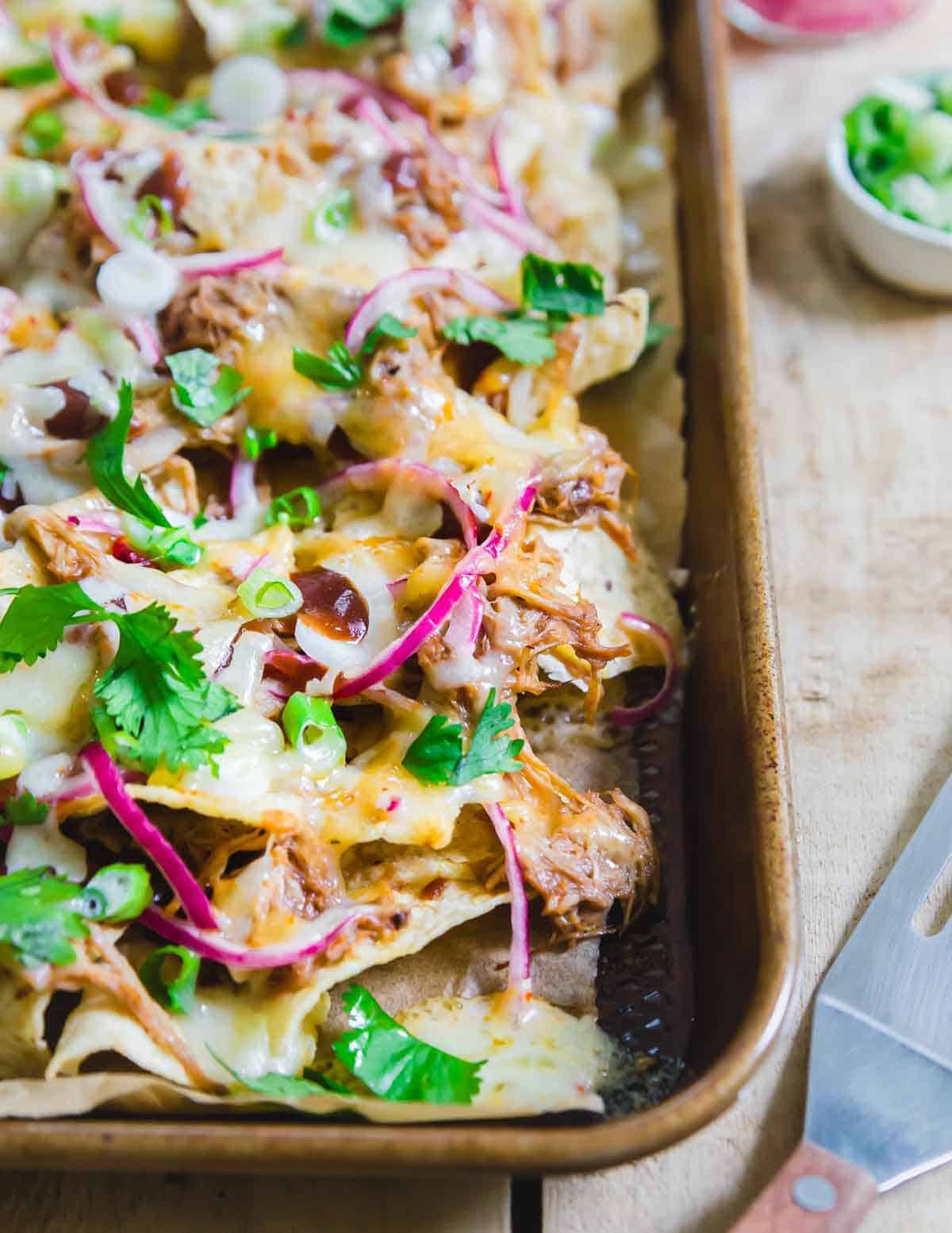 Pulled pork nacho recipe with pickled onions, cheddar cheese and lots of sweet BBQ sauce.