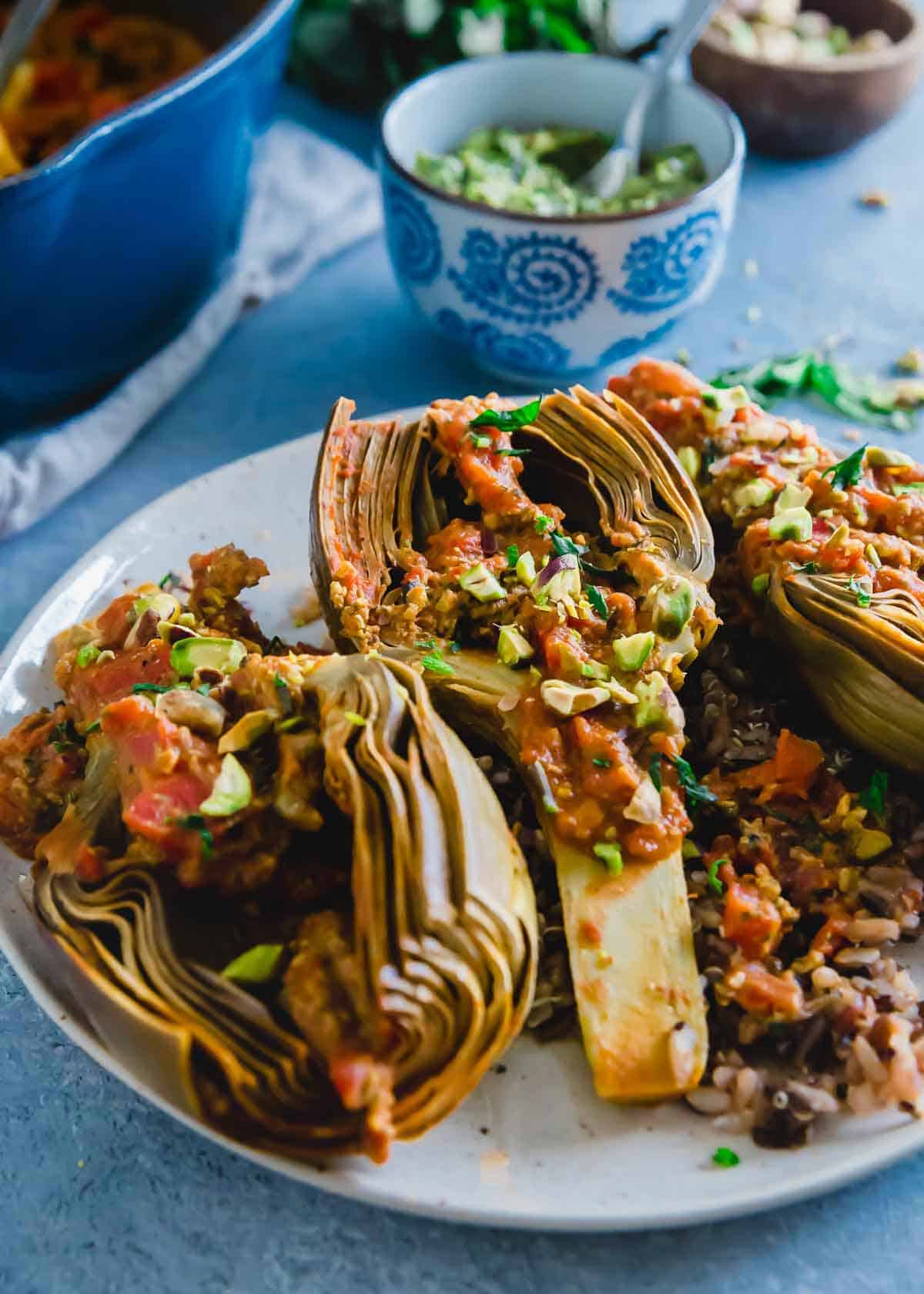 Simple tomato braised artichokes cooked until tender and served with a pistachio basil pesto.