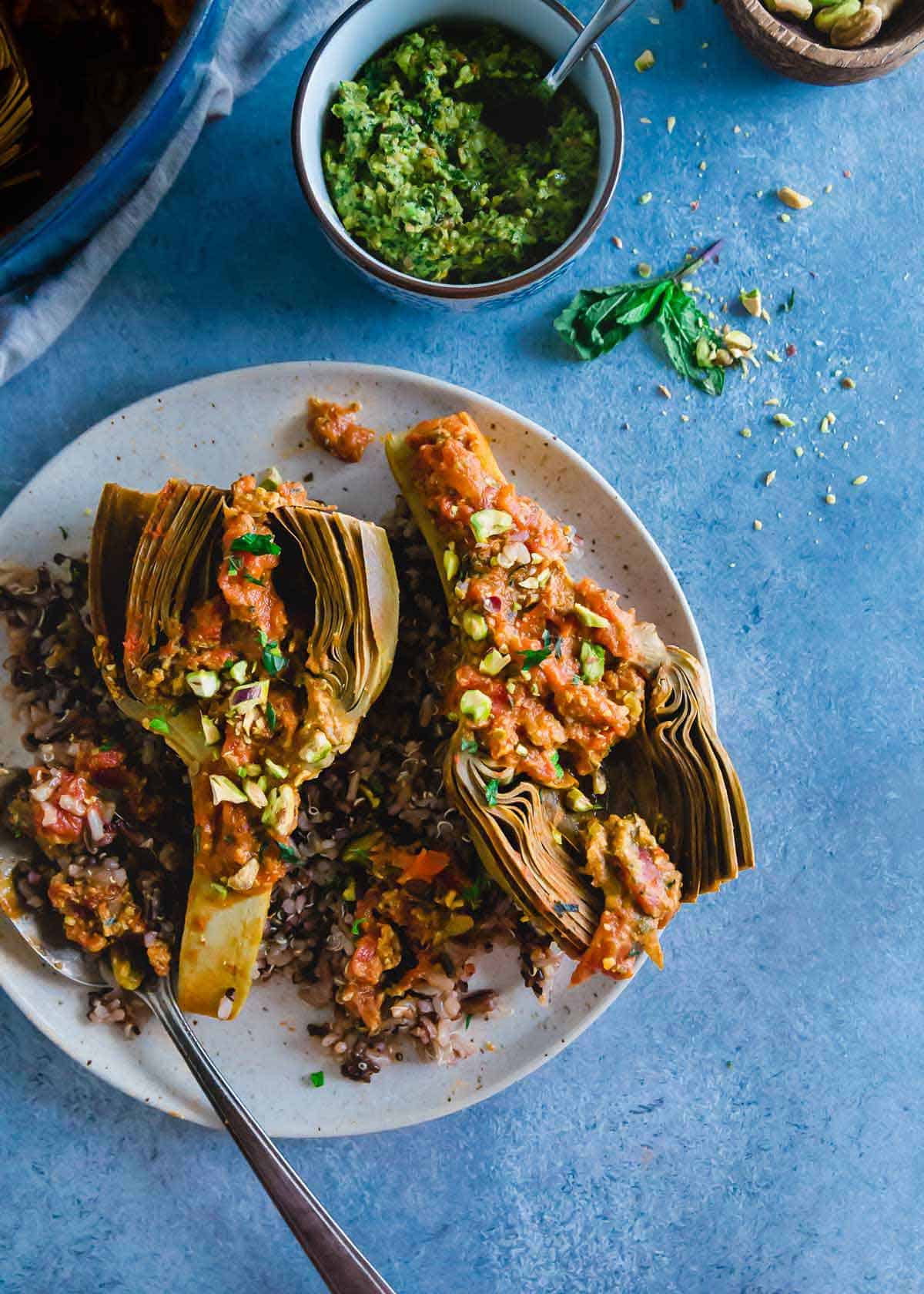 An easy recipe for braised artichokes with a chunky white wine tomato sauce and a bright pistachio pesto.