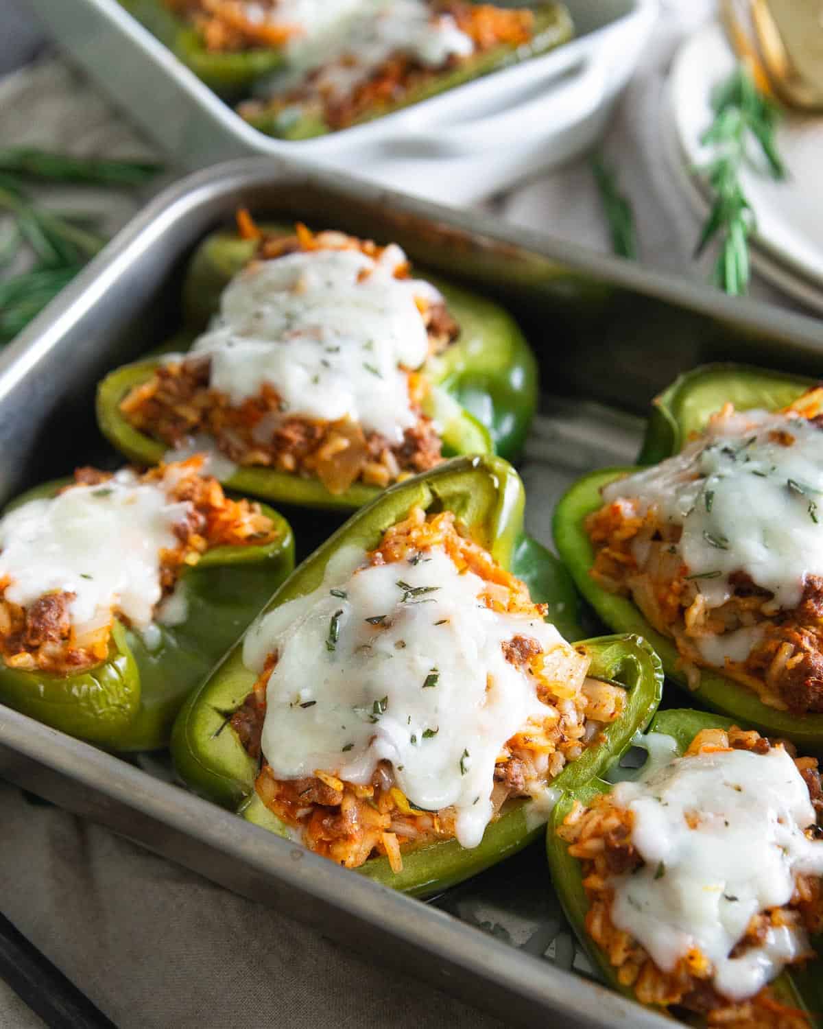 Lean protein packed ground bison stuffed peppers are filled with rice, shredded zucchini, carrot, onion and tomato sauce for a deliciously hearty meal with a melted cheesy topping.