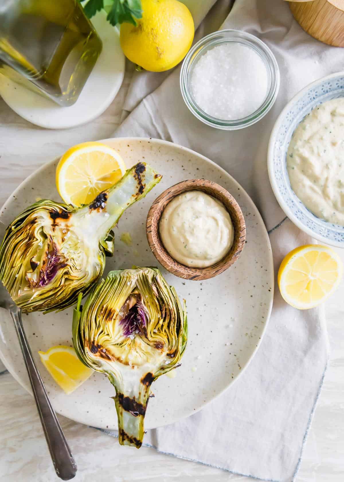Looking for a new way to enjoy eating artichokes? Try grilling them with this simple recipe! The smoky grilled charred flavor goes perfectly with a bright tahini lemon dipping sauce.