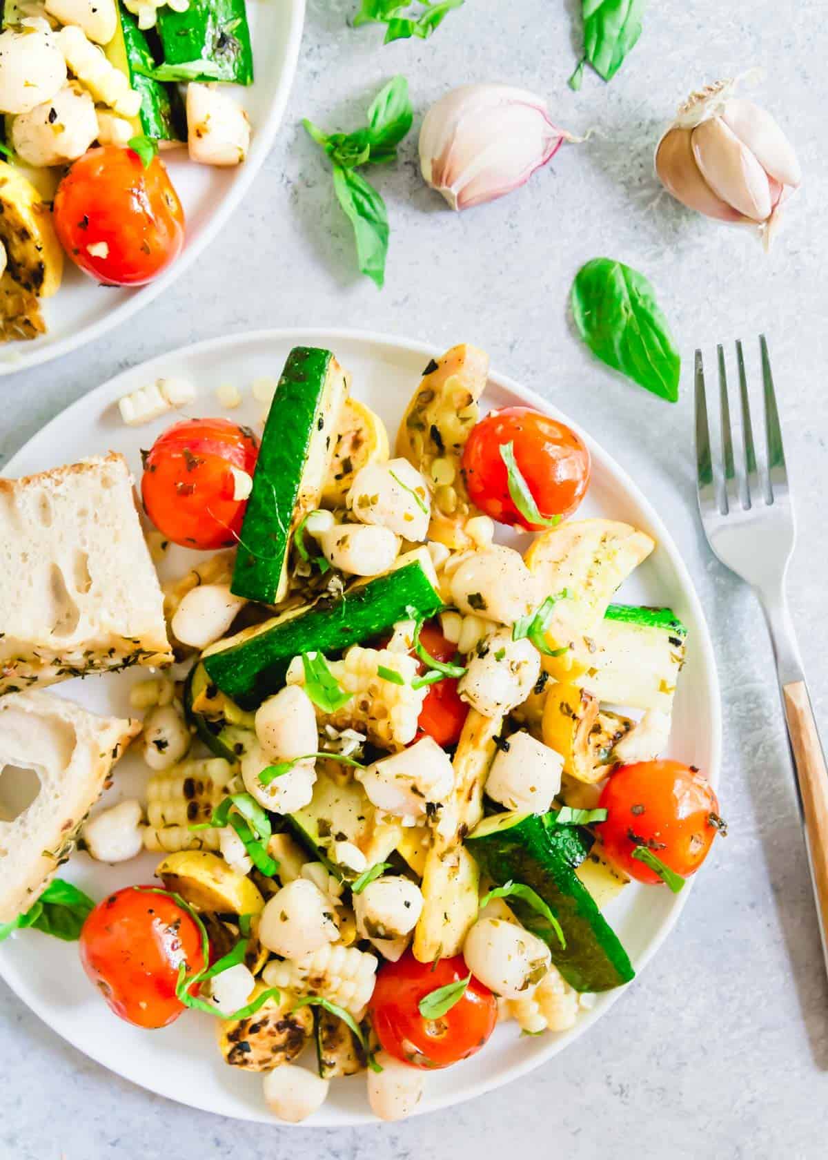 A summer meal made completely on the grill! These grilled bay scallops with zucchini, corn and tomatoes are tossed in a simple and delicious garlic basil butter sauce.