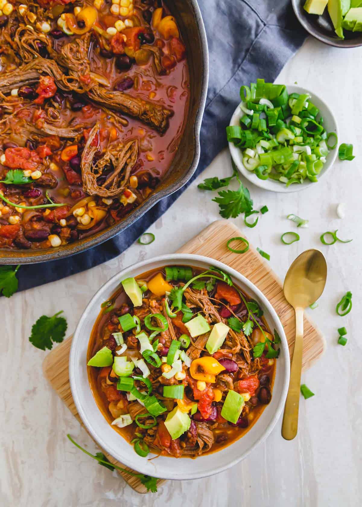 Meaty beef brisket chili is topped with avocado, cilantro and green onions.