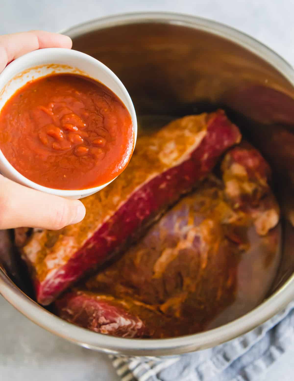 BBQ sauce is added to the Instant Pot on top of the brisket before cooking.