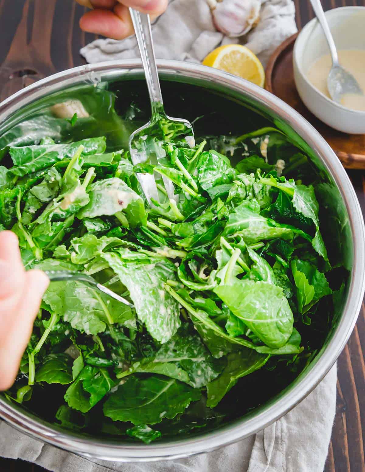 I verdi di baby kale sono saltati in un condimento al limone, aglio e tahini con lievito nutrizionale.