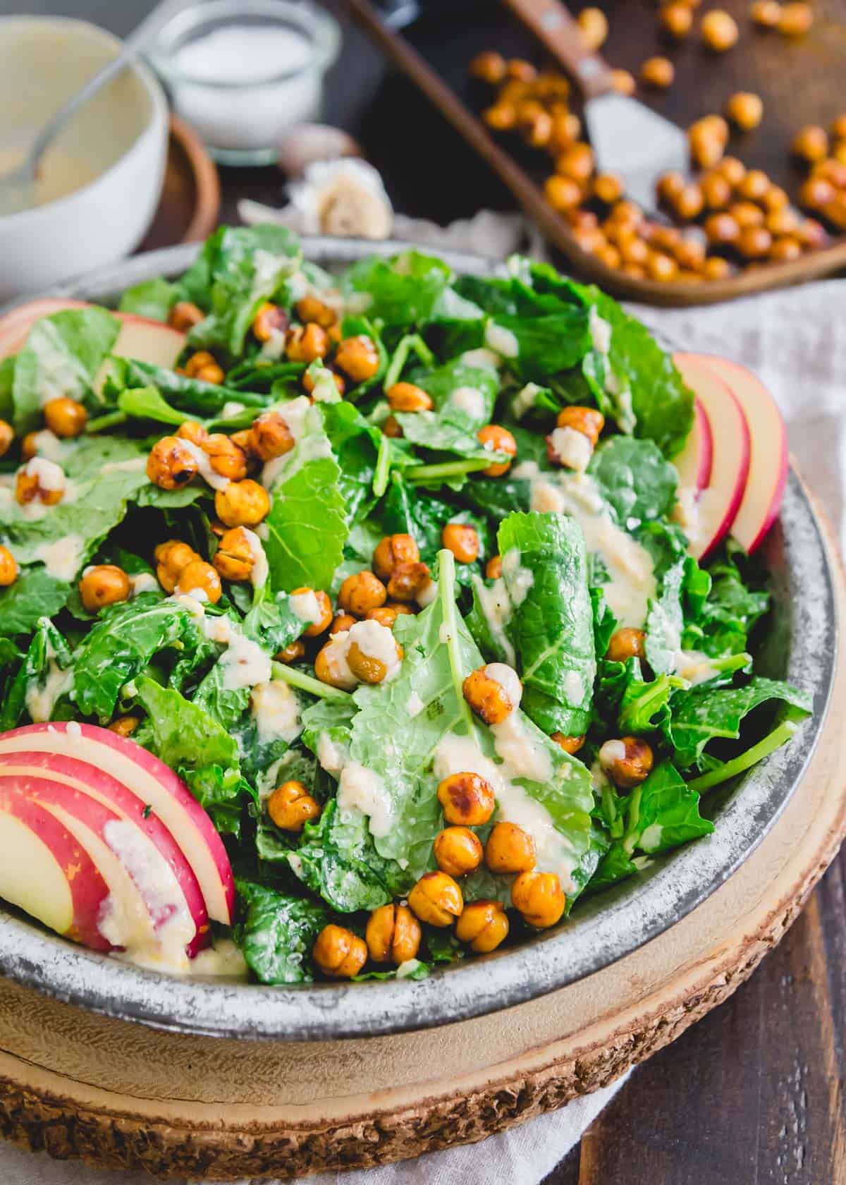  A melhor receita de degustação para uma salada de couve bebé rápida e fácil! Atirada num simples molho de tahini e coberta com grão de bico assado e fatias de maçã, é uma refeição completa à base de plantas com pouco esforço.